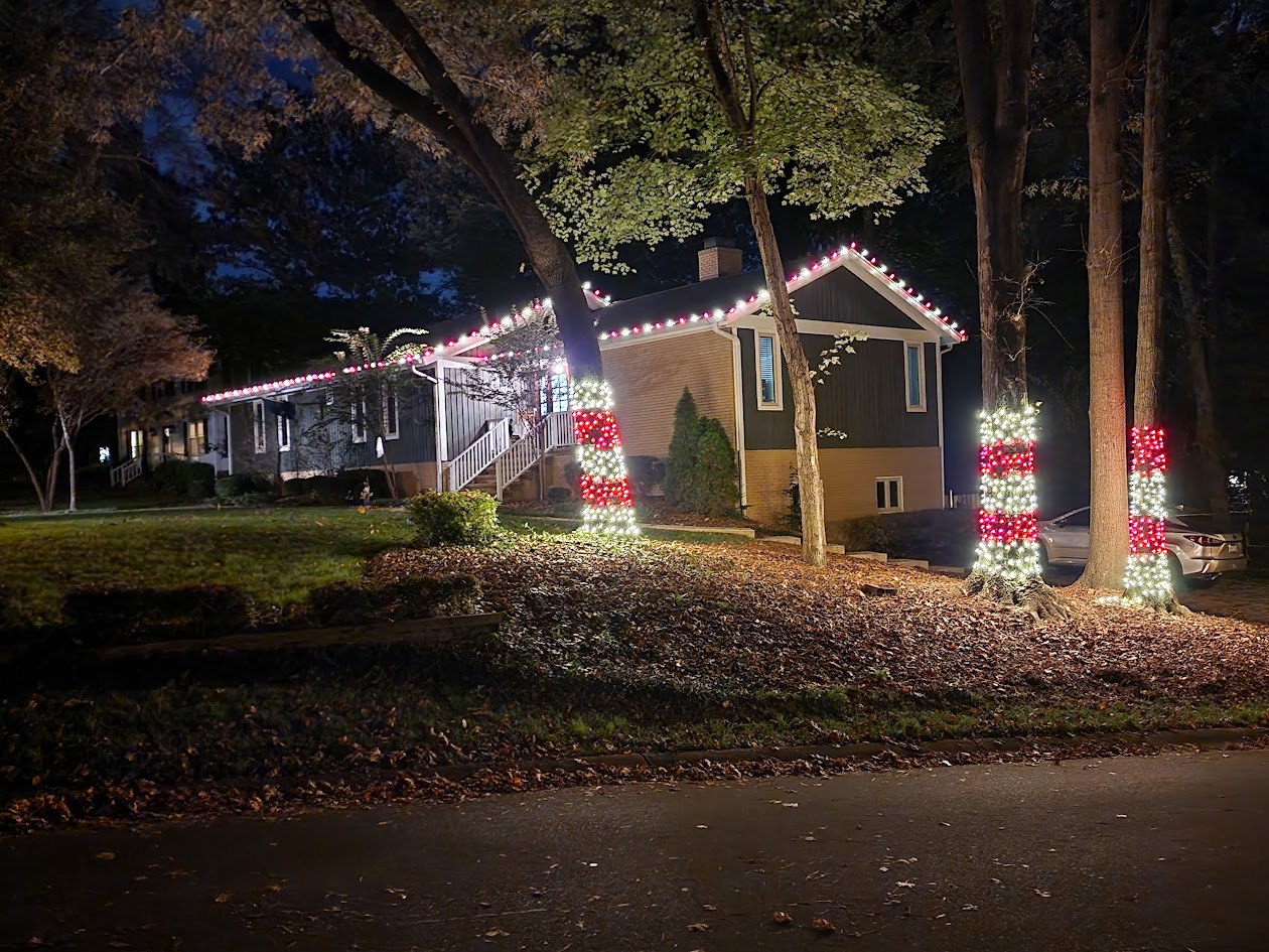 Red and warm white roofline and tree lighting on a Charlotte home