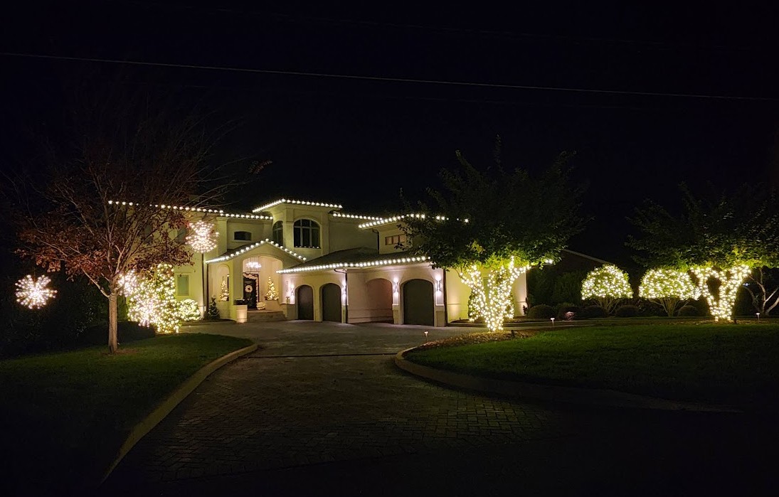 Warm white roofline, tree, shrub, and starburst lighting on a Cornelius home
